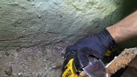 Angle grinder cutting the old cast iron stack, sparks against the basement wall